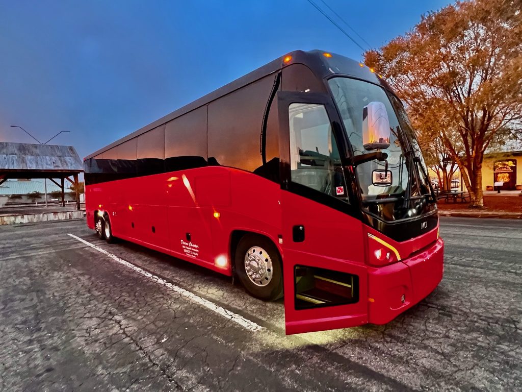 Red and black MCI charter bus parked on a street